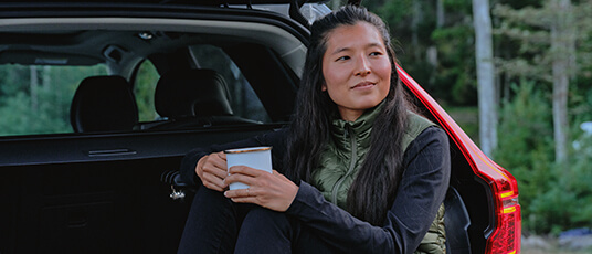 Woman relaxing in her Volvo enjoying coffee