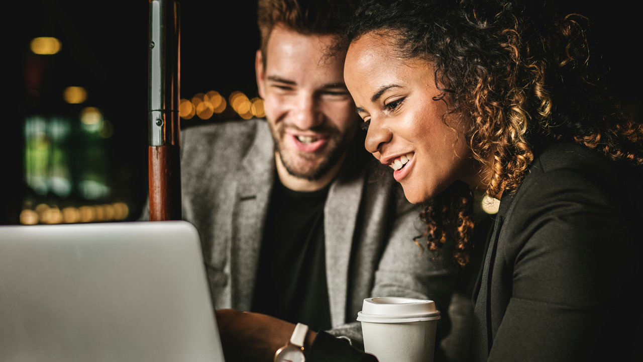 Mixed couple looking at laptop with coffee