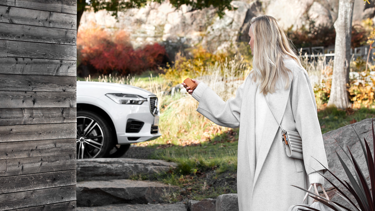 Blonde woman with key and Volvo in fall
