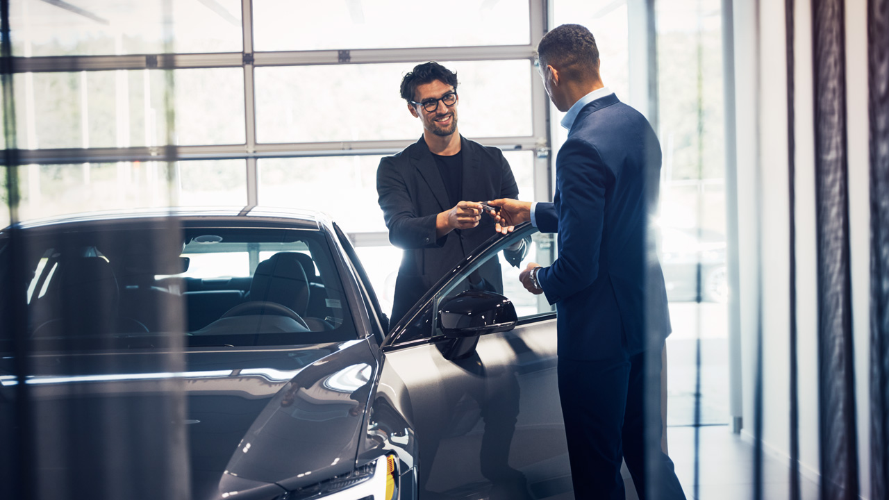 Volvo salesman handing key to customer