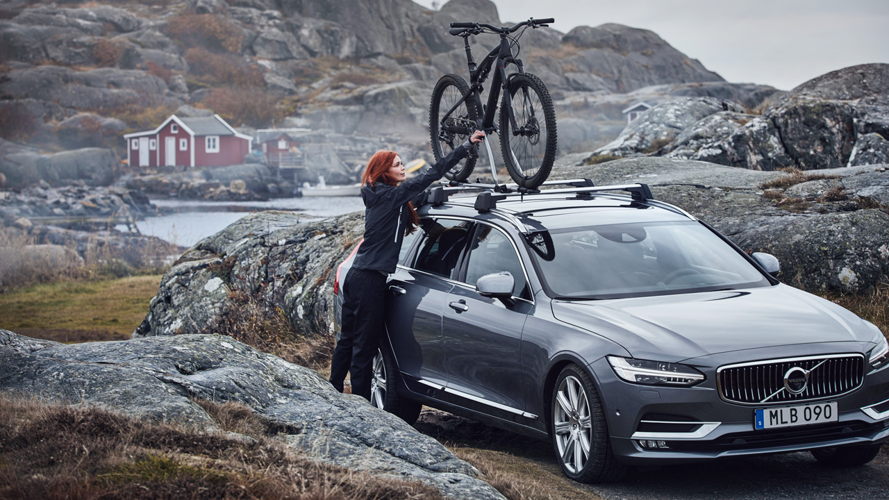 Woman putting bike on V90 countryside